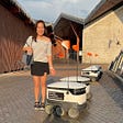 Precious Yamaguchi stands near a row of delivery robots in Estonia