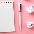 Image of Blank notepad, pen and crumpled paper balls