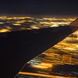 Wing of an aeroplane over blurred lights of city