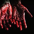 A person’s hands covered with blood.