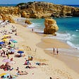 Picture of a beach (Portugal) with people and umbrellas.