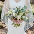 woman in wedding dress holding bouquet of white flowers and eucalyptus