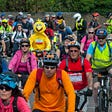 Big yellow bird in the middle of a crowd of bicyclists.