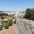 A section of stone wall from the Castelo de Bragança (Braganza Castle). Behind it is the city skyline and hills of the city of Bragança.