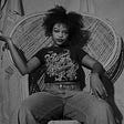 Charmaine Ejelonu sits in a wicker chair in a black-and-white image