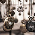 Photo of different antique pocket-watches hanging.