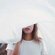 Woman’s face partially covered by white sheet