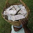 An elderly woman carries a basketful of obsolete Zimbabwean banknotes on her head.