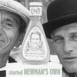 Black and white photo of Hotchner and Newman on either side of a Newman’s Own bottle