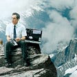 Ben Stiller as Walter Mitty sitting on top of a mountain with his open briefcase.