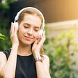 A girl wearing black sleeveless headphones enjoying music with closed eyes