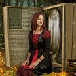 In the middle of the forest stands an open book. Kneeling in front of the open pages is a young woman dressed in an old fashioned dress of red and black that laces up the front. Surroinding both the book and woman is the magical circle made up of the written words of the story.