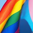An LGBT pride flag against a transgender pride flag.