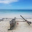 rickety old boat on shore of white sand beach