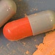 Orange and grey pill capsules containing powdered LSD
