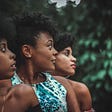 Three Black women looking over their shoulder