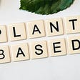 A picture of the phrase 'plant-based' on a white backdrop beside two green leaves