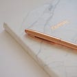 A golden pen on a white journal for people ready to explore their creativity