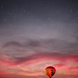 hot air balloon floating in the dawn sky with stars overhead