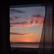 Pink dawn over the horizon seen through a window with curtains | Check out Lifelog — golifelog.com