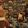 A room filled with books and a woman contemplating the titles