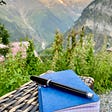 A pen sits on a notebook overlooking the swiss alps.