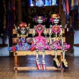 Three day of the dead Mexican puppets sitting on a wooden bench