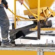 A construction worker is doing cold weather concreting by pouring concrete in winter.