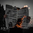 Human holding burning newspaper