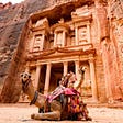 A photo of a camel with the city of Petra (Jordan) in the background
