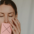 Image of woman with an adhesive square shaped piece of paper on her lips. There’s an “x” on the piece of paper to symbolize silence.