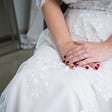 A bride’s hands are folded in her lap, engagement ring adorning her rouge painted fingers. Feels hopeful, expectant.