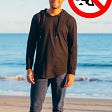 Latino man standing on the beach with sunglasses. Sign of dog pooping with x in it near him