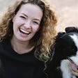 Woman holding two dogs and laughing with joy.