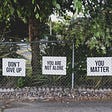 Signs on a fence that say “Don’t Give Up,” “You are not alone” and “You Matter”