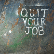 Quit Your Job spray painted on a wood floor.