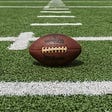A closeup of a football on the grass of a football field