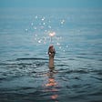 Image of person underwater holding a sparkler above the water.
