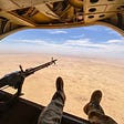An image of a Chinook helicopter flying over the desert.