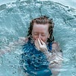 Woman holding her nose as she jumps in the pool.
