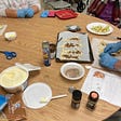 A table with baking ingredients and gloved hands preparing stuffed crescent rolls to go in to the oven