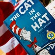 The book, “The Cat in The Hat,” by Dr. Seuss, sits on a book shelf