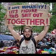 Occupy Wall Street demonstator with sign "I love humanity! Let's figure this shit out together!"