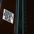 Photo of a Birds Aren’t Real sticker on the back of a street sign.