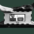 Two hands on top of the Touchbox, a connection & musical interface that invites a PwD and their informal carer to sit together and generate music through physical contact.
