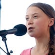 Activist Greta Thunberg speaking into a microphone as she leads the Youth Climate Strike.