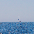 a sail boat with colored sails along the horizon line