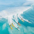 Six surfers riding a huge wave
