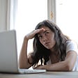 Woman sitting at laptop looking confused