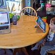 Child looking at ipad while adult computer is open